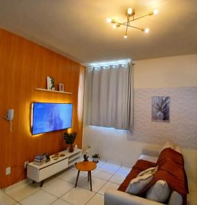 a living room with a couch and a tv on a wall at Apartamento COP 30 in Ananindeua