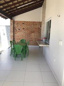 un patio con sedie verdi, un tavolo e un muro di mattoni di Casa de Praia Coqueiro - Luís Correia, Piauí a Luis Correia
