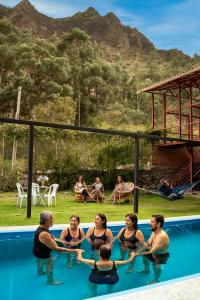 a group of people sitting in the water in a swimming pool at Eco Lodge Cabañas con Piscina in Urubamba