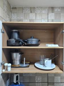 Un estante de madera con ollas, sartenes y tazas. en Casa Recife Conforto 10, en Recife