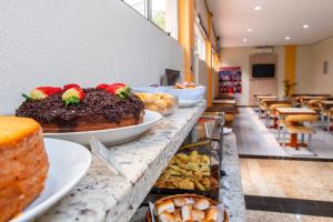 a bakery with cakes and pastries on a counter at Hotel Express São Leopoldo in São Leopoldo