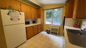a kitchen with a white refrigerator and a sink at Spacious Woods Hole Beach Retreat in Falmouth