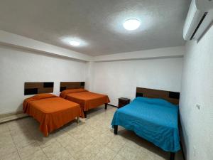 zwei Betten in einem Zimmer mit orangefarbener und blauer Bettwäsche in der Unterkunft Microhotel Ciudad del Carmen in Ciudad del Carmen