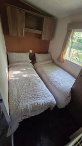 Dos camas en un dormitorio pequeño con ventana. en California Breeze, en Scratby 18 fotos más