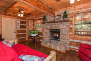 a living room with a stone fireplace in a cabin at The Settlement by American Patriot Getaways in Williamsburg