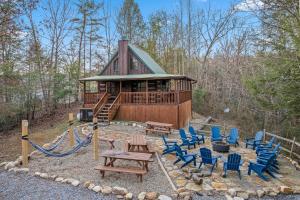 a log cabin with blue chairs and a picnic table at The Settlement by American Patriot Getaways in Williamsburg