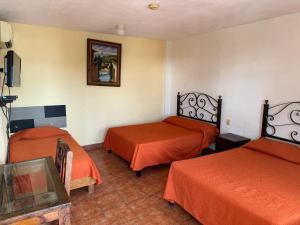 Zimmer mit 2 Betten und orangefarbener Bettwäsche in der Unterkunft Microhotel Ciudad del Carmen in Ciudad del Carmen