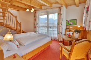 a bedroom with a bed and a table and a window at Hotel Astoria in Serfaus