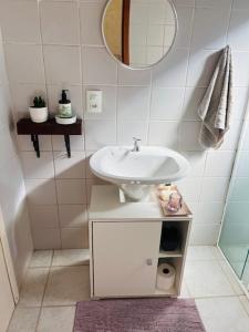 a white bathroom with a sink and a mirror at Estúdio térreo nas margens da Lagoa in Florianópolis +11 photos