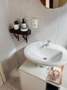 a white bathroom with a sink and a mirror at Estúdio térreo nas margens da Lagoa in Florianópolis +12 photos