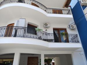 a white building with two balconies and two windows at Olga Luxury Apartment in Paralia Katerinis