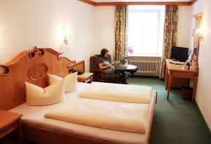 
a hotel room with two beds and a desk at Post-Hotel in Mittenwald
