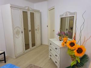 a room with a dresser with a mirror and flowers at RDR Apartments in Santa Catharina