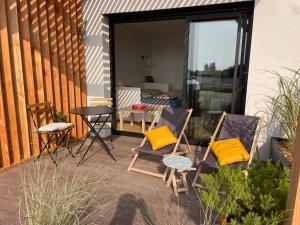 a patio with two chairs and a table with yellow pillows at Appartement bord de mer in Lampaul-Plouarzel +13 photos