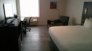 a hotel room with a bed and a desk and a chair at HOM Hotel Gainesville, SureStay Collection by Best Western in Gainesville