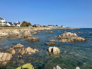 un gruppo di rocce nell'acqua con case di Le Galion Beach a Le Croisic