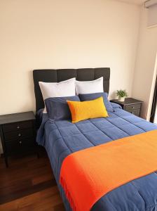 ein Bett mit einer orange-blauen Decke und Kissen in der Unterkunft Miraflores habitaciones con baño privado especial para turistas in Lima