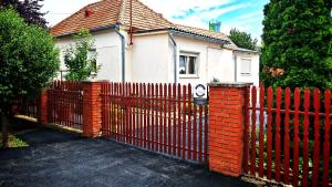 a red fence in front of a house at Ezee Rider Apartmanok in Sárvár