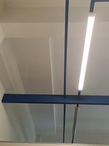 a glass ceiling with a blue beam and a light at Lugar único in Dourados