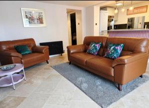 Una sala de estar con un sofá de cuero marrón y una mesa. en North Devon Luxe Gem for 4, 2 Ensuite Beds, Elegantly Renovated Sea Nearby, en Ilfracombe