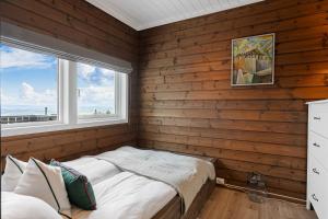 a bedroom with wooden walls and a bed with a window at Fagertoppen 1314B by Vacation Trysil in Mælem