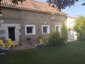 a house with two chairs and a grill in a yard at La fermette de Chandigon in Antran