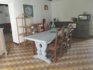 a dining room table with chairs and a clock on the wall at La fermette de Chandigon in Antran