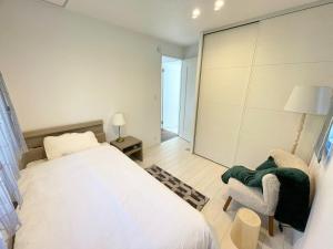 a bedroom with a white bed and a chair at Akikawa Villas1 - Vacation STAY 18834 in Yuge +2 photos