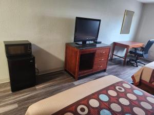 a hotel room with a bed and a television on a dresser at Airport Inn Flint Airport in Flint