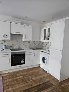 a kitchen with white cabinets and a washer and dryer at Northampton RoomKey in Northampton +5 photos