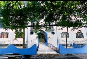 a white building with a blue door and stairs at Apto no centro de Maringa com garagem in Maringá