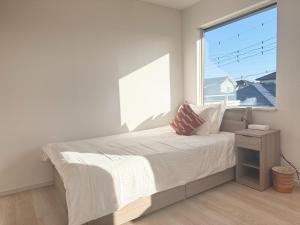 a white bedroom with a bed and a large window at Akikawa Villas14 - Vacation STAY 18847 in Fukumoto