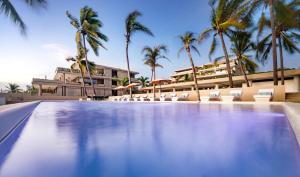 a swimming pool in front of a hotel with palm trees at Anera Villas in Barra de Potosi +10 photos