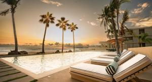 a resort swimming pool with lounge chairs and palm trees at Anera Villas in Barra de Potosi