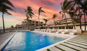a resort swimming pool with palm trees and a building at Anera Villas in Barra de Potosi