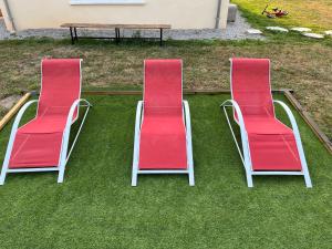 two red chairs sitting on the grass next to a table at La villa Lambert - Le Loft in La Ferté-Fresnel