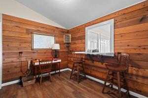 a room with a wooden wall with a desk and chairs at Little Birds Nest in Highlands