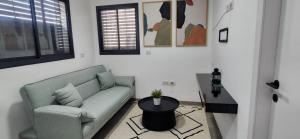 ein Wohnzimmer mit Sofa und Tisch in der Unterkunft Rell's Heart in Kirjat Schmona