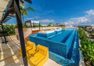 a swimming pool with yellow lounge chairs next to a building at The best location in Playa Downtown 2Br Condo in Playa del Carmen +26 photos