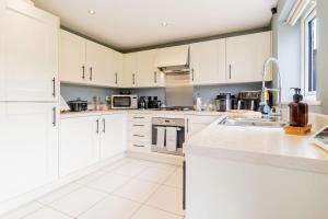 eine Küche mit weißen Schränken und einer Spüle in der Unterkunft Three Bedroom Birmingham Stay Free Parking Perfect for Families Travellers Professionals M6 in Birmingham + 4 Fotos
