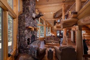 a living room with a stone fireplace in a log cabin at Little Deschutes Wildlife Lodge - Nature's Cabin in La Pine +46 photos