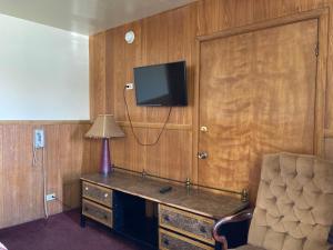 a room with a desk with a tv and a chair at Highland Manor Motel in Lombard