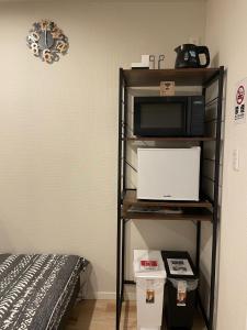a room with a microwave and a bed at T-HOTEL Iriya - Vacation STAY 94122v in Tokyo