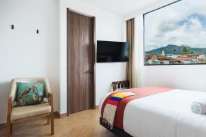 a bedroom with a bed and a chair and a window at Hotel Casa Tama in Salento