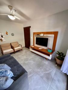 a living room with a couch and a television at Casa térrea em condomínio à 500m da praia do Peró in Cabo Frio +49 photos