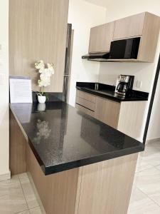 a kitchen with a black counter top in a room at Marina Cerritos - Blanco Celeste - 5 Albercas in Mazatlán