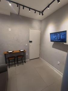 a room with a table and a television on the wall at Apartamento á 1200m da Praia de Itapua in Vila Velha