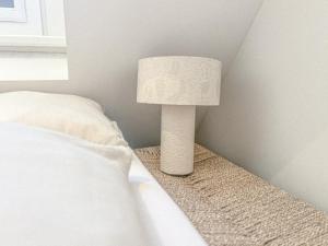 a white lamp sitting next to a bed at Studio No3 in Katwijk aan Zee