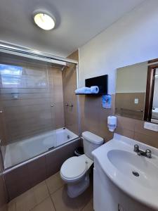 a bathroom with a toilet and a tub and a sink at Hotel Versailles in Ambato