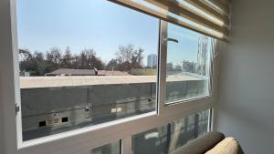ein Fenster in einem Zimmer mit Blick auf ein Gebäude in der Unterkunft Movistar Arena, Parq OHiggins Estacionamiento Gratis in Santiago